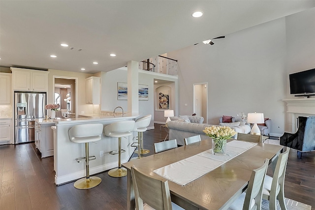 23907 Birchwood Lake Ln, Katy, TX 77493 - dining room featuring dark wood-style flooring, a fireplace, recessed lighting, baseboards, and a towering ceiling
