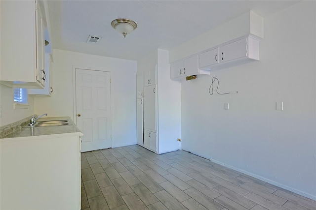 washroom with light wood-style floors, visible vents, baseboards, and a sink