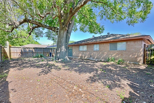 back of house with brick siding and a fenced backyard