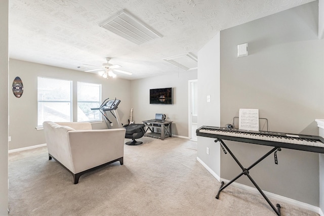 living area featuring light colored carpet, attic access, a textured ceiling, and ceiling fan