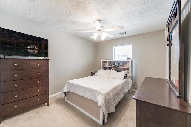 bedroom with light colored carpet, a textured ceiling, visible vents, and ceiling fan