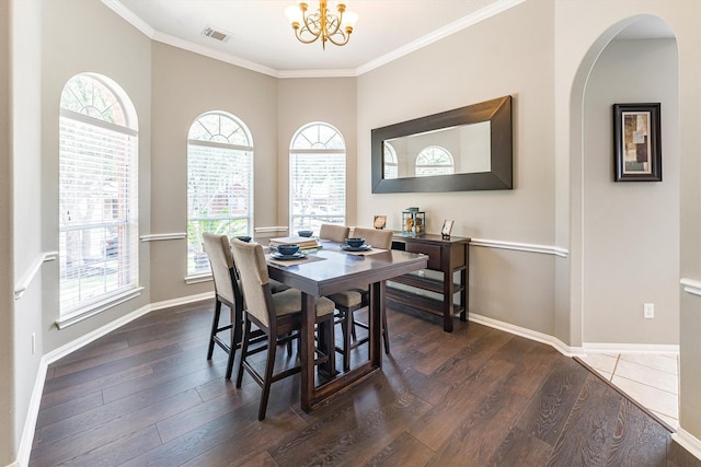 dining room with ornamental molding, an inviting chandelier, visible vents, and wood finished floors