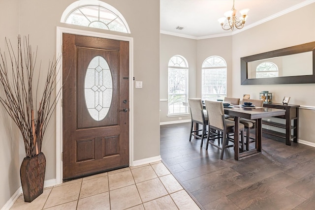 entrance foyer featuring a notable chandelier, baseboards, visible vents, crown molding, and wood finished floors
