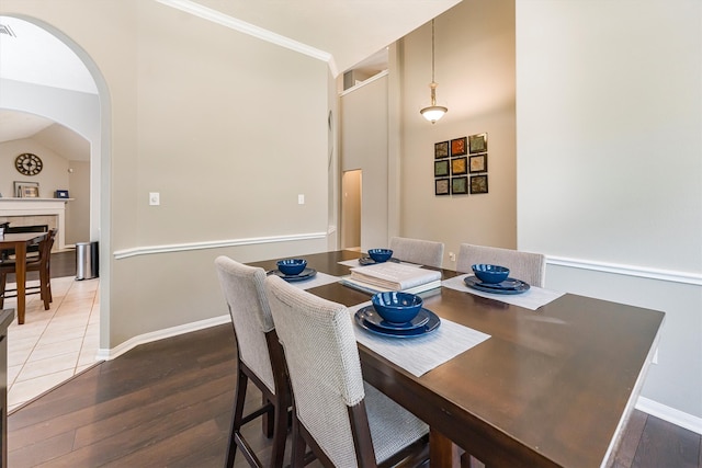 dining area featuring baseboards, visible vents, wood finished floors, arched walkways, and a fireplace