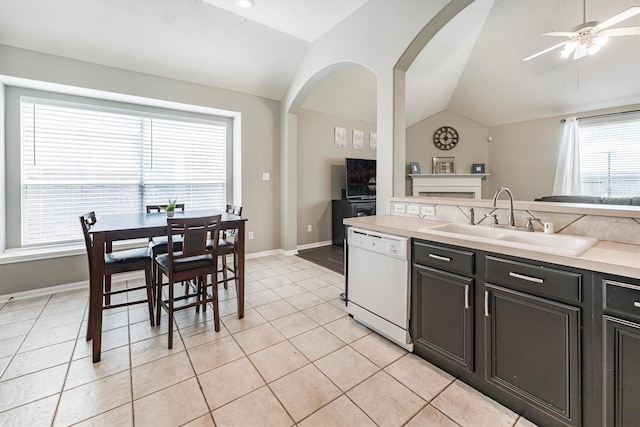 kitchen with a ceiling fan, a sink, light countertops, lofted ceiling, and white dishwasher