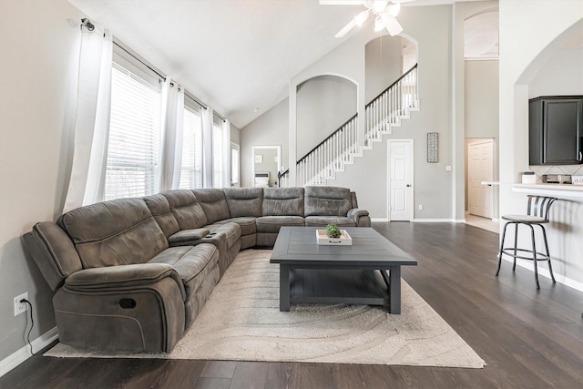 living area with ceiling fan, baseboards, arched walkways, and dark wood finished floors