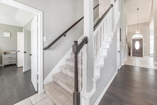 foyer entrance featuring wood finished floors, baseboards, ornamental molding, and stairs