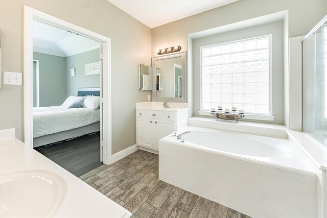 ensuite bathroom featuring wood finished floors, vanity, baseboards, connected bathroom, and a garden tub