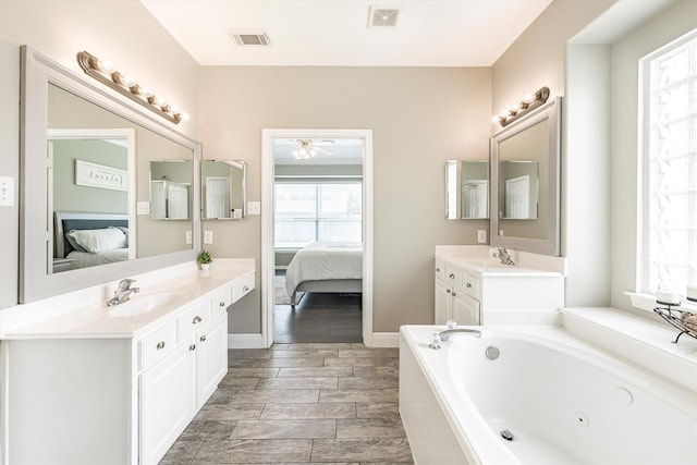 ensuite bathroom featuring a sink, visible vents, ceiling fan, a whirlpool tub, and connected bathroom