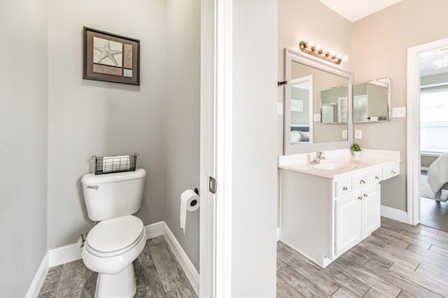 bathroom featuring toilet, ensuite bath, baseboards, and wood finished floors