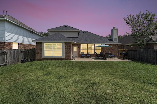 back of property featuring a yard, a patio area, a shingled roof, and a fenced backyard