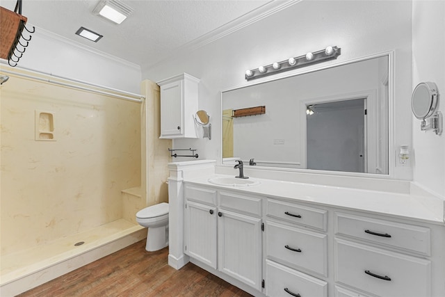 bathroom with toilet, wood finished floors, crown molding, a shower stall, and vanity