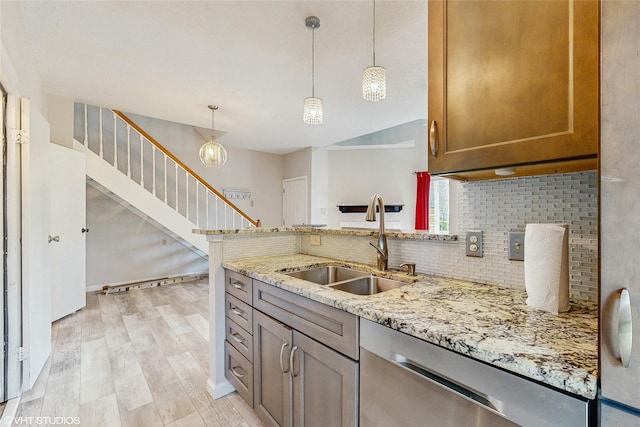 kitchen featuring a sink, light stone counters, light wood-style flooring, backsplash, and stainless steel dishwasher