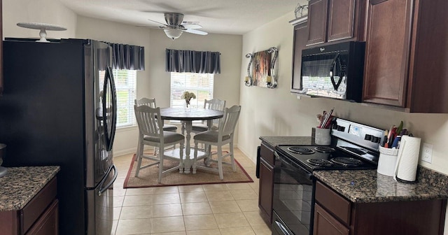 22706 Threefold Ridge Dr, Hockley, TX 77447 - kitchen with black appliances, a ceiling fan, light tile patterned floors, dark brown cabinetry, and dark stone counters