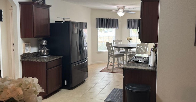 kitchen featuring freestanding refrigerator, light tile patterned floors, ceiling fan, dark brown cabinetry, and dark countertops