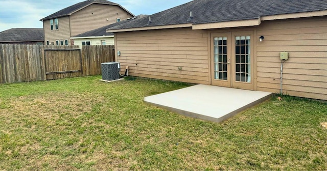back of property featuring roof with shingles, a patio area, fence, central AC, and a yard