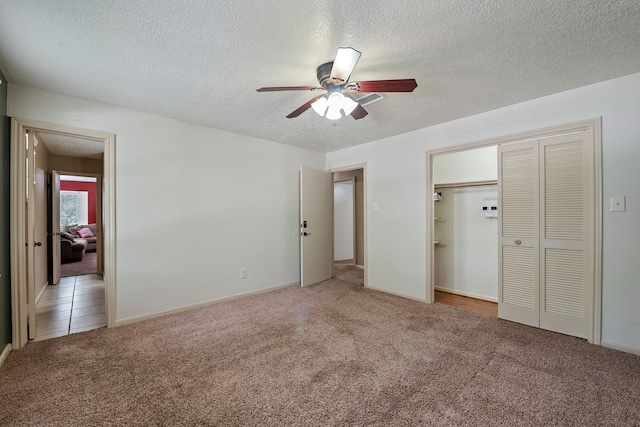 unfurnished bedroom with a ceiling fan, a closet, a textured ceiling, baseboards, and light colored carpet