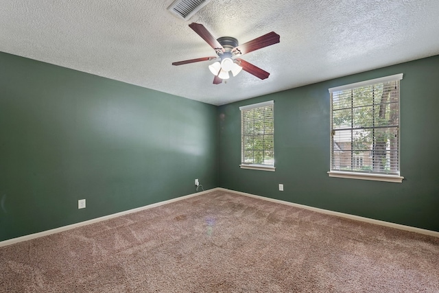 carpeted empty room with ceiling fan, a textured ceiling, baseboards, and visible vents