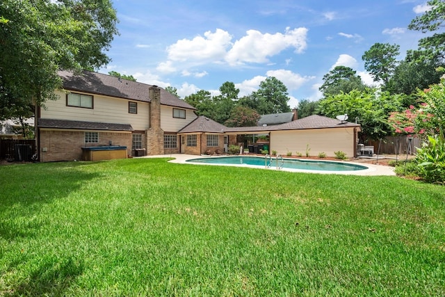 exterior space with a yard, a hot tub, fence, and a patio