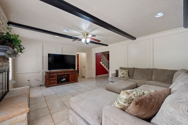 living area featuring a decorative wall, a textured ceiling, stairway, ceiling fan, and light tile patterned floors