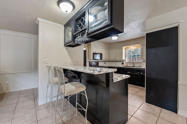 kitchen with a sink, a peninsula, a textured ceiling, and black appliances