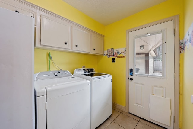 washroom featuring cabinet space, light tile patterned floors, and washer and dryer