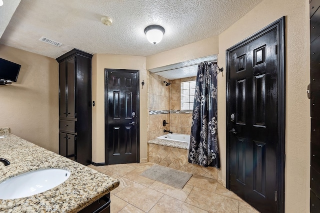 bathroom featuring tiled shower / bath combo, a textured ceiling, visible vents, tile patterned flooring, and vanity