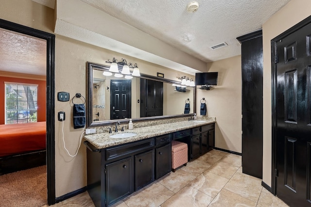 bathroom featuring a sink, visible vents, a textured ceiling, and double vanity