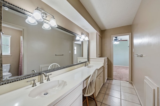 full bathroom featuring toilet, tile patterned floors, double vanity, and a sink