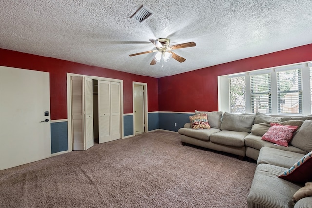 carpeted living room with a ceiling fan, visible vents, and a textured ceiling