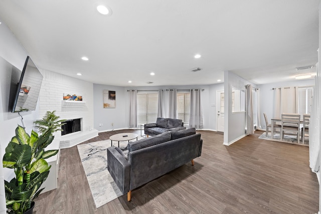 living room with recessed lighting, baseboards, visible vents, a brick fireplace, and wood finished floors