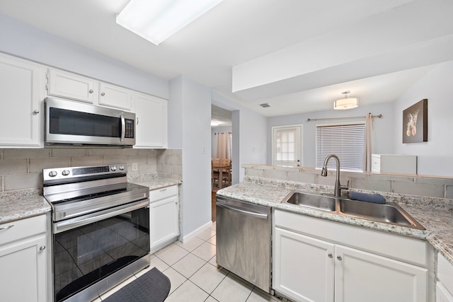 kitchen with a sink, white cabinets, appliances with stainless steel finishes, decorative backsplash, and light tile patterned flooring