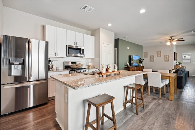 25388 Leather Leaf Ct, Montgomery, TX 77316 - kitchen with stainless steel appliances, tasteful backsplash, dark wood-style flooring, a kitchen bar, and open floor plan