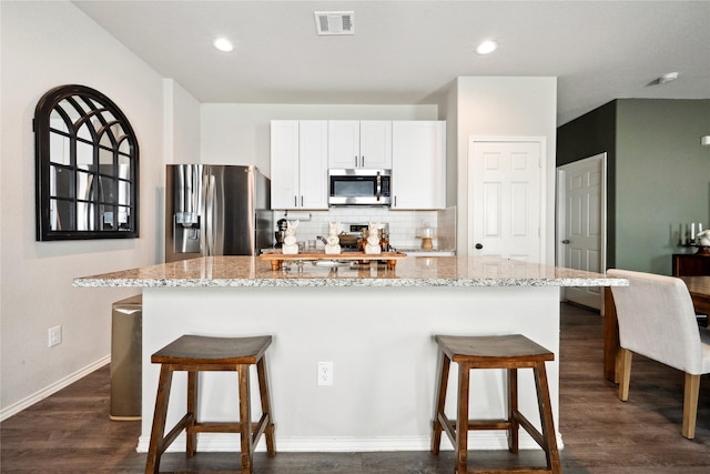 25388 Leather Leaf Ct, Montgomery, TX 77316 - kitchen featuring an island with sink, stainless steel appliances, a kitchen breakfast bar, visible vents, and tasteful backsplash