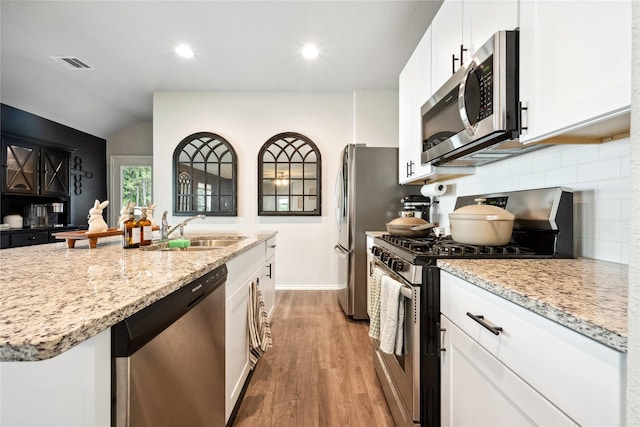 25388 Leather Leaf Ct, Montgomery, TX 77316 - kitchen with a sink, visible vents, light wood finished floors, backsplash, and appliances with stainless steel finishes