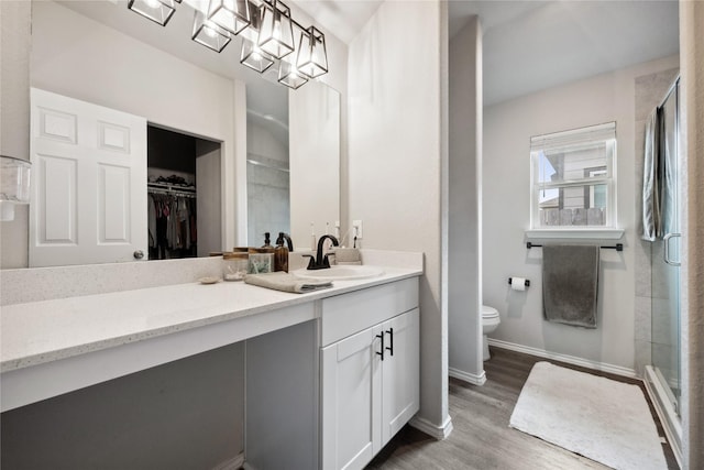 25388 Leather Leaf Ct, Montgomery, TX 77316 - bathroom with a stall shower, baseboards, toilet, vanity, and wood finished floors