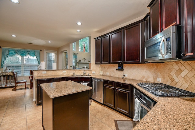 kitchen with a sink, stainless steel appliances, a wealth of natural light, and light stone countertops