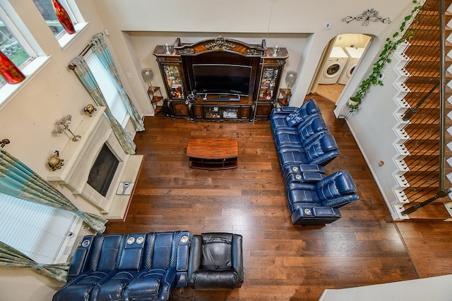 living area with washing machine and dryer, a towering ceiling, arched walkways, and wood finished floors