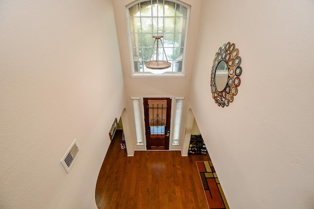 entryway featuring a high ceiling, arched walkways, visible vents, and wood finished floors