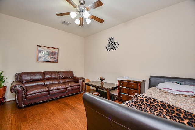 bedroom with a ceiling fan, baseboards, visible vents, and wood finished floors