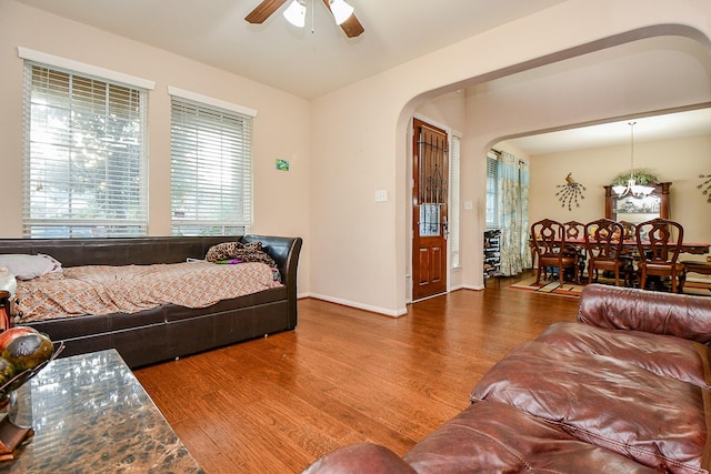 living room with baseboards, wood finished floors, a ceiling fan, and arched walkways