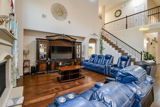 living room featuring visible vents, a towering ceiling, and hardwood / wood-style floors