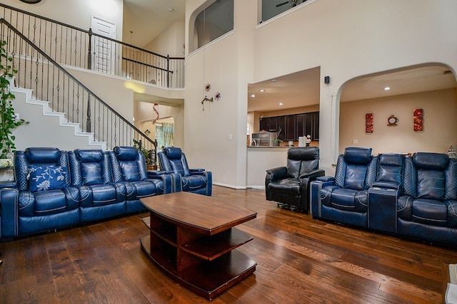 living area featuring recessed lighting, stairs, arched walkways, hardwood / wood-style floors, and a high ceiling