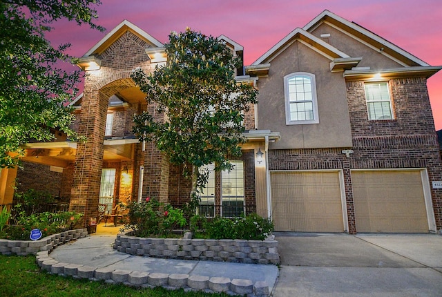 view of front of house with concrete driveway, stucco siding, brick siding, and an attached garage