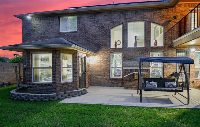 back of property featuring a yard, a patio area, and brick siding