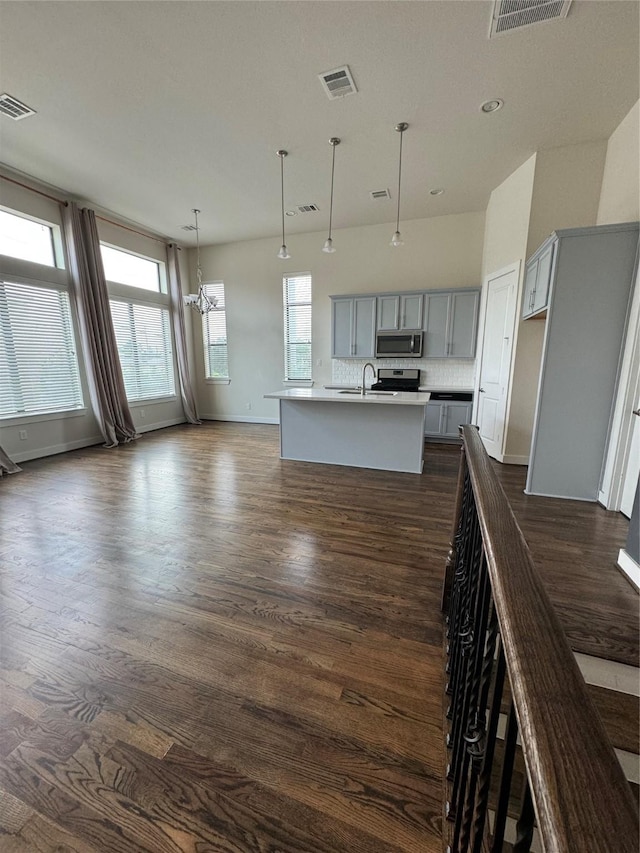 kitchen featuring an island with sink, visible vents, gray cabinetry, appliances with stainless steel finishes, and dark wood-style floors