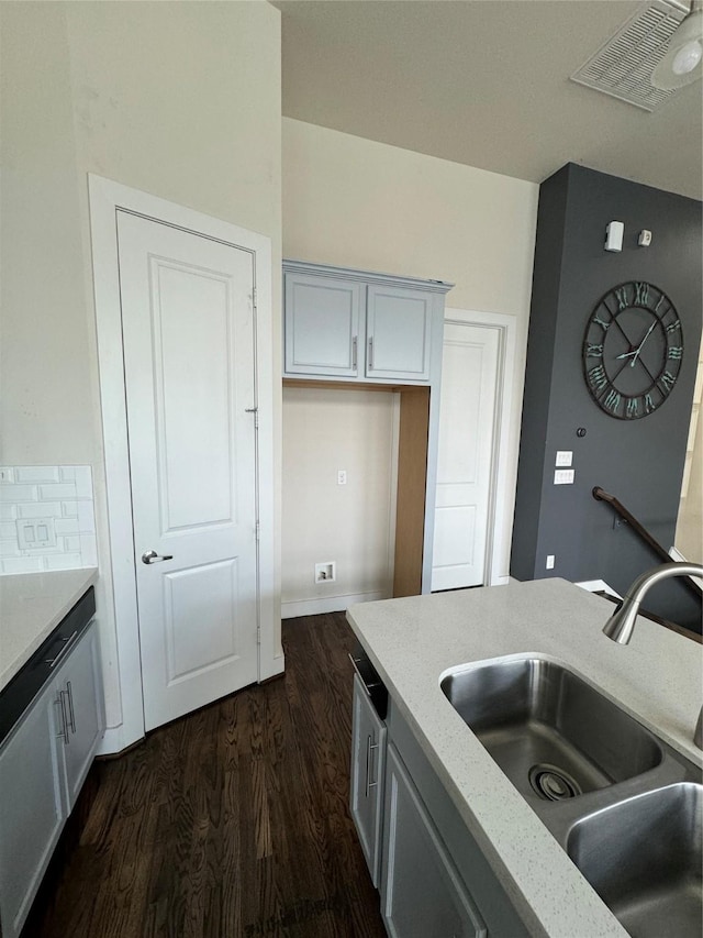 kitchen featuring light stone counters, visible vents, dark wood-style flooring, and a sink