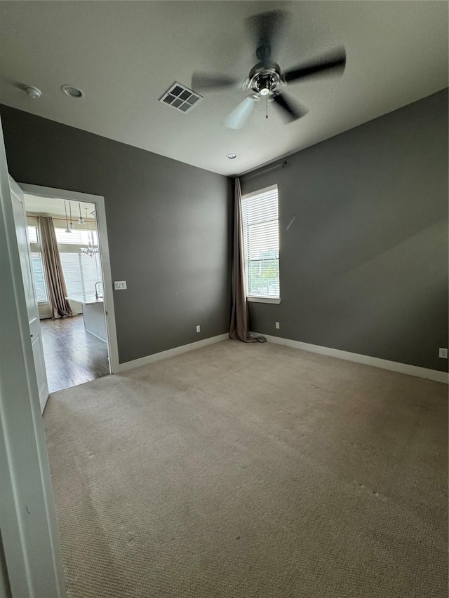 carpeted empty room featuring visible vents, baseboards, and ceiling fan