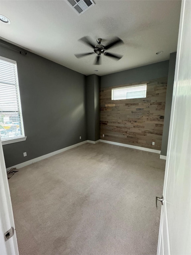 spare room with wood walls, carpet, baseboards, and visible vents