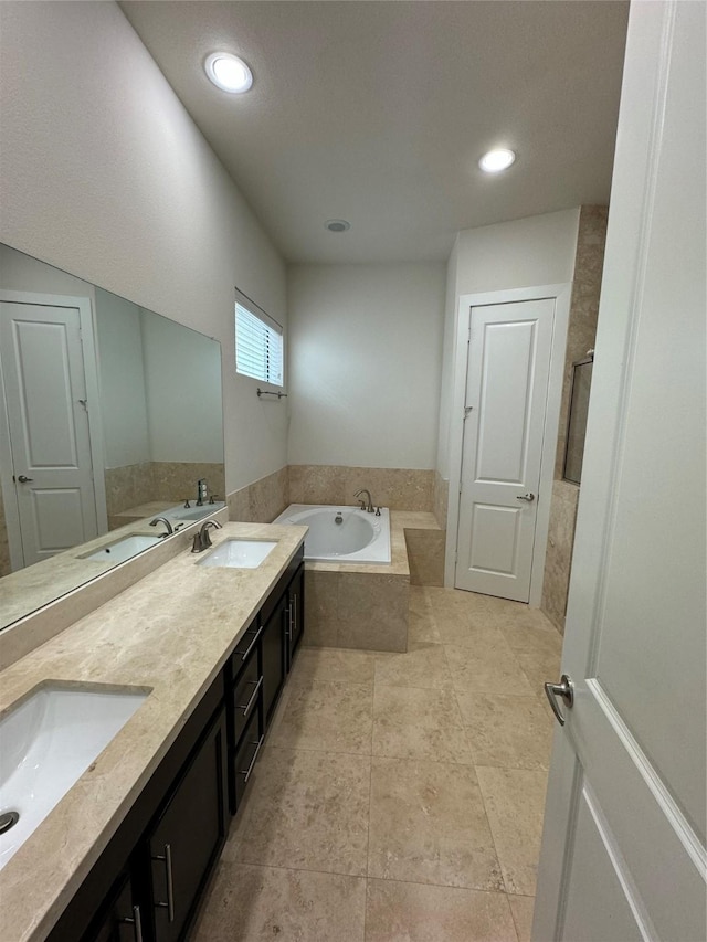 bathroom featuring recessed lighting, a garden tub, double vanity, and a sink